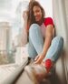 A smiling woman sits casually by the window