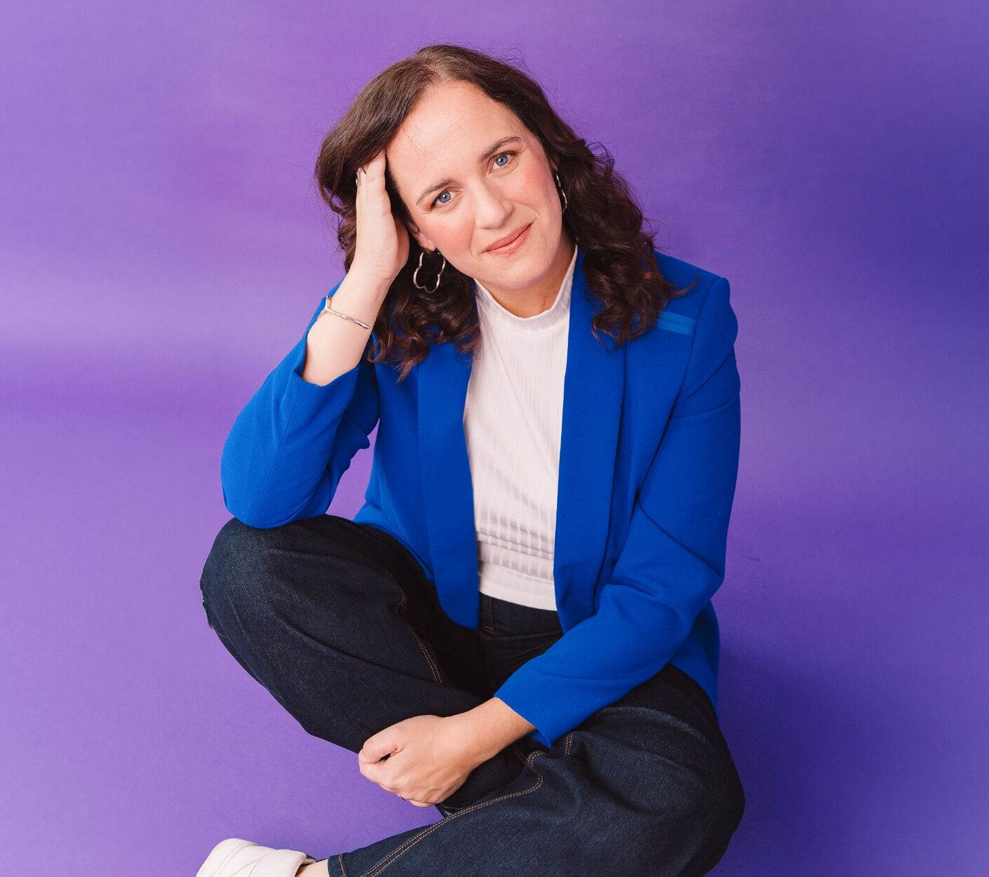 Katrin Siemens steht in einer blauen Bluse vor einem modernen Gebäude und hält ihre rechte Hand auf einem Geländer